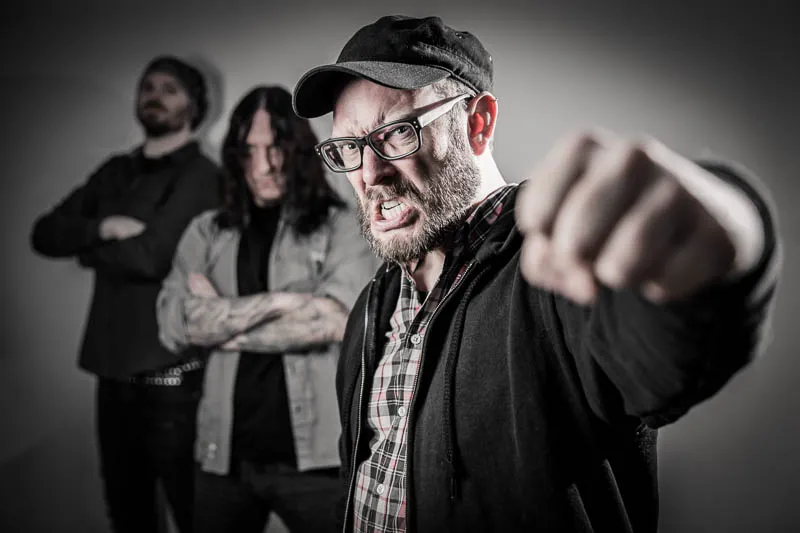 Schwarz weiß Portrait einer dunkelhaarigen Frau mit Locken Mähne. Die Frau trägt elegante weiße Spitzenunterwäsche, hat den Kopf nach hinten über eine weiße Sofalehne gelegt und blickt direkt in die Kamera, welche leicht von oben auf Ihr Gesicht gerichtet ist.